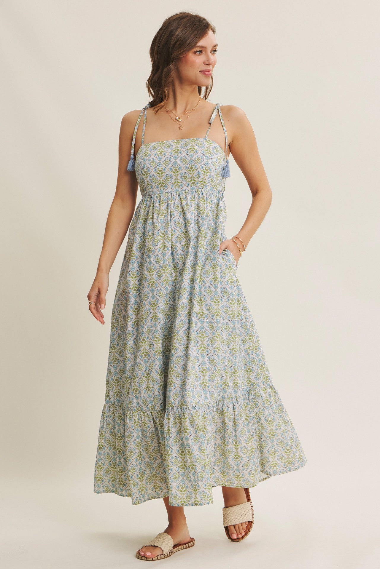 woman wearing a blue and green patterned maxi dress with adjustable straps and pockets