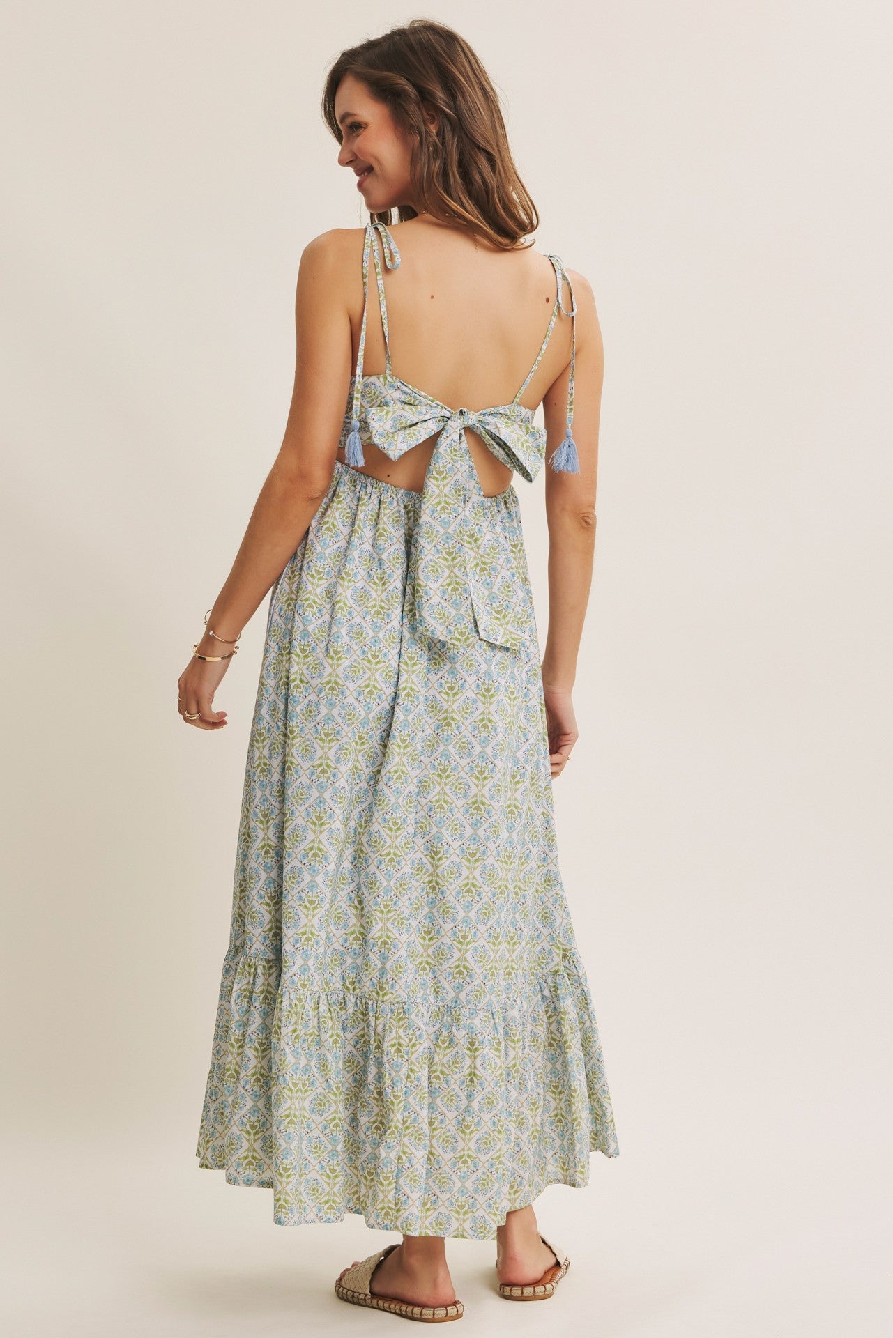 woman wearing a backless floral maxi dress with a tie closure and tassel details