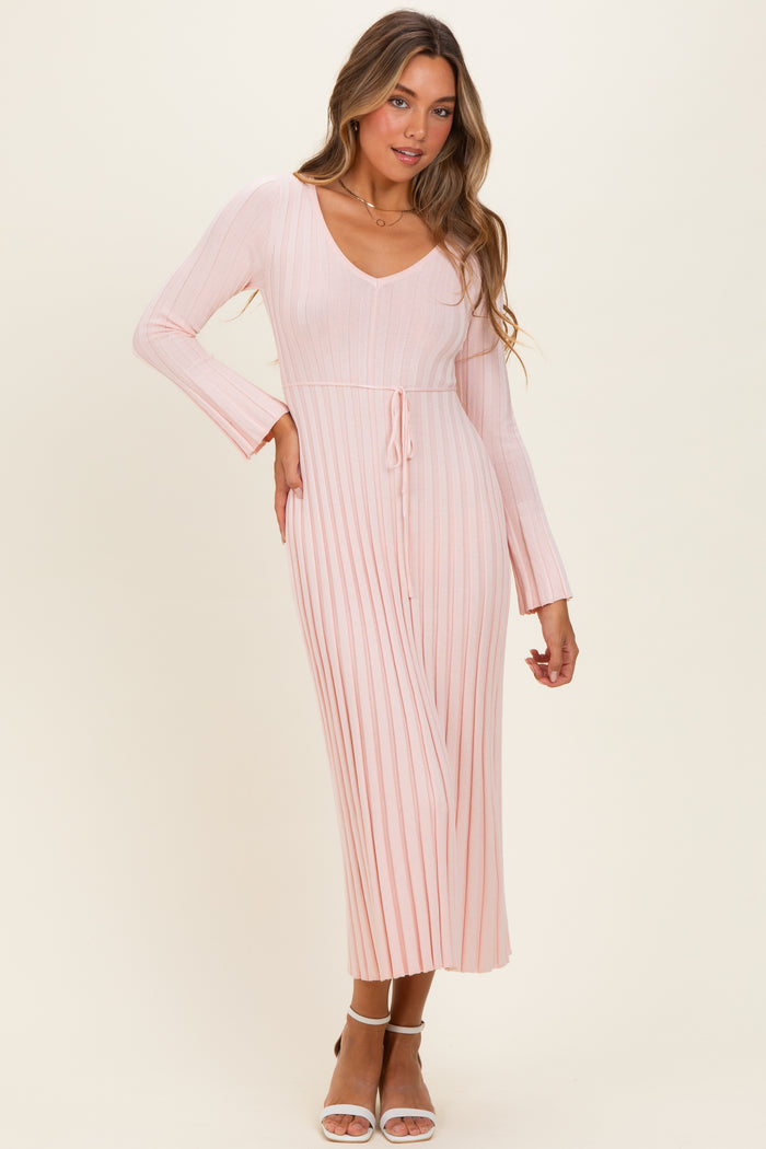 woman wearing a pink ribbed long sleeve midi dress with a v-neck and tie waist detail