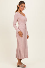 woman wearing a long sleeve ribbed pink dress with a drawstring waist and side slits, standing against a neutral background
