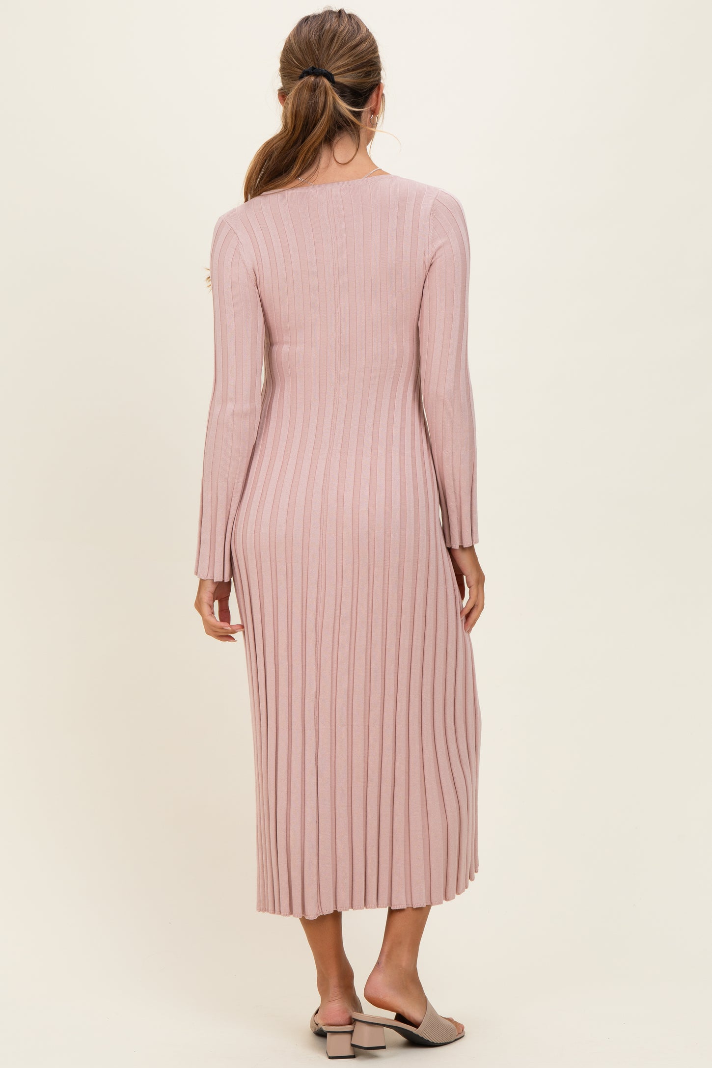 woman wearing a pink ribbed long sleeve midi dress, viewed from the back