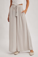 woman wearing light grey wide-leg pants with a drawstring waist and side pockets