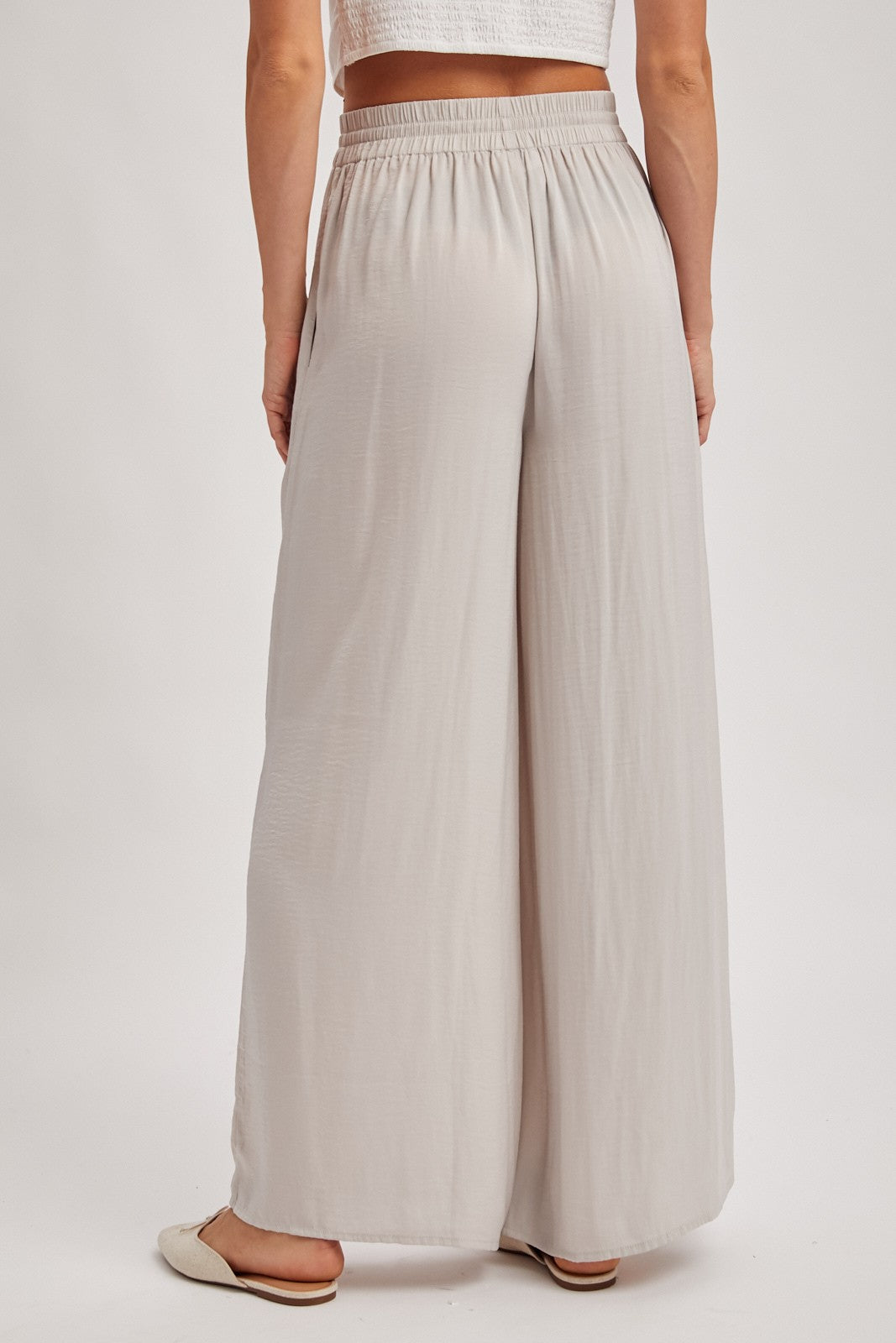 woman wearing light gray wide-leg pants with an elastic waistband, viewed from the back