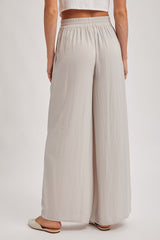 woman wearing light gray wide-leg pants with an elastic waistband, viewed from the back