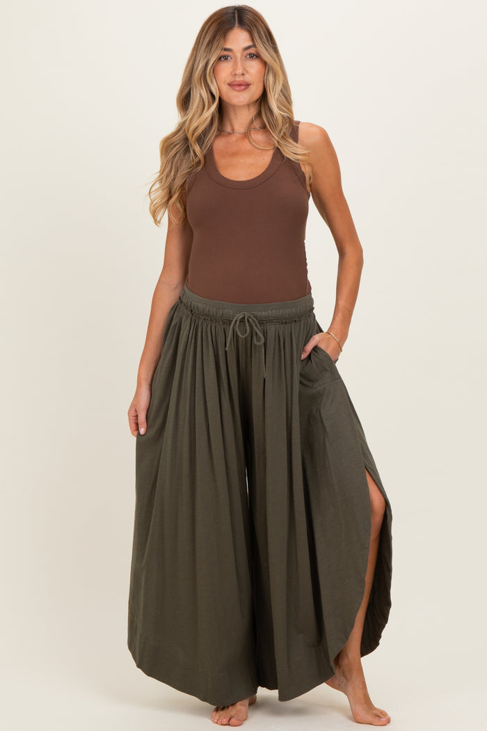 woman wearing a brown ribbed maternity tank top and olive green wide-leg maternity pants with side slits