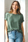 woman wearing a green short sleeve relaxed fit top paired with light blue jeans and smiling