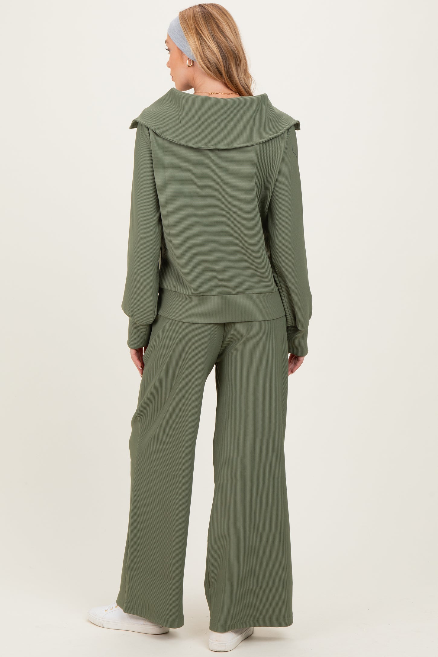 woman wearing a green ribbed maternity lounge set with wide-leg pants and an oversized collar pullover, showing her baby bump