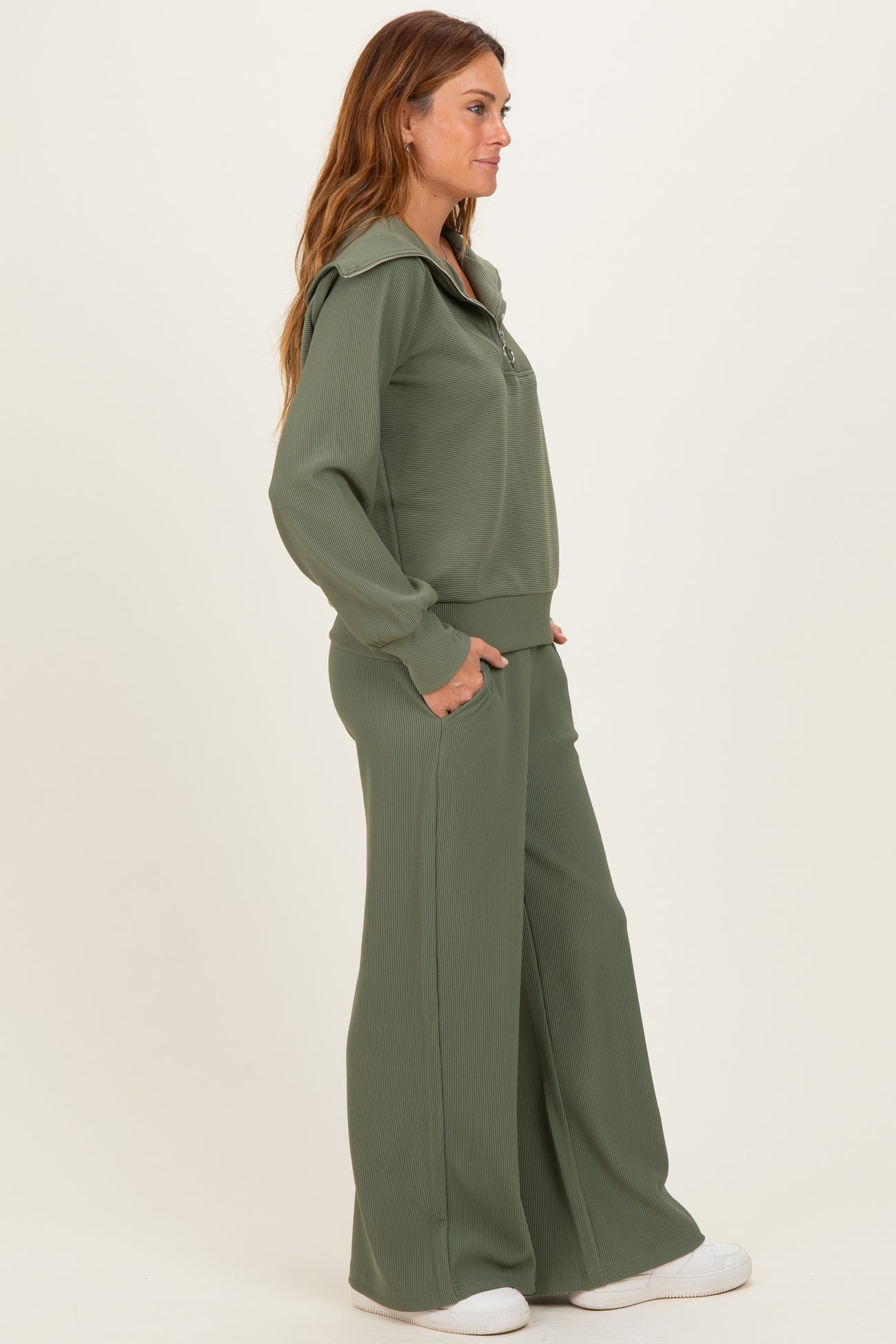 woman wearing an olive green ribbed lounge set with a zip-up collar and wide-leg pants