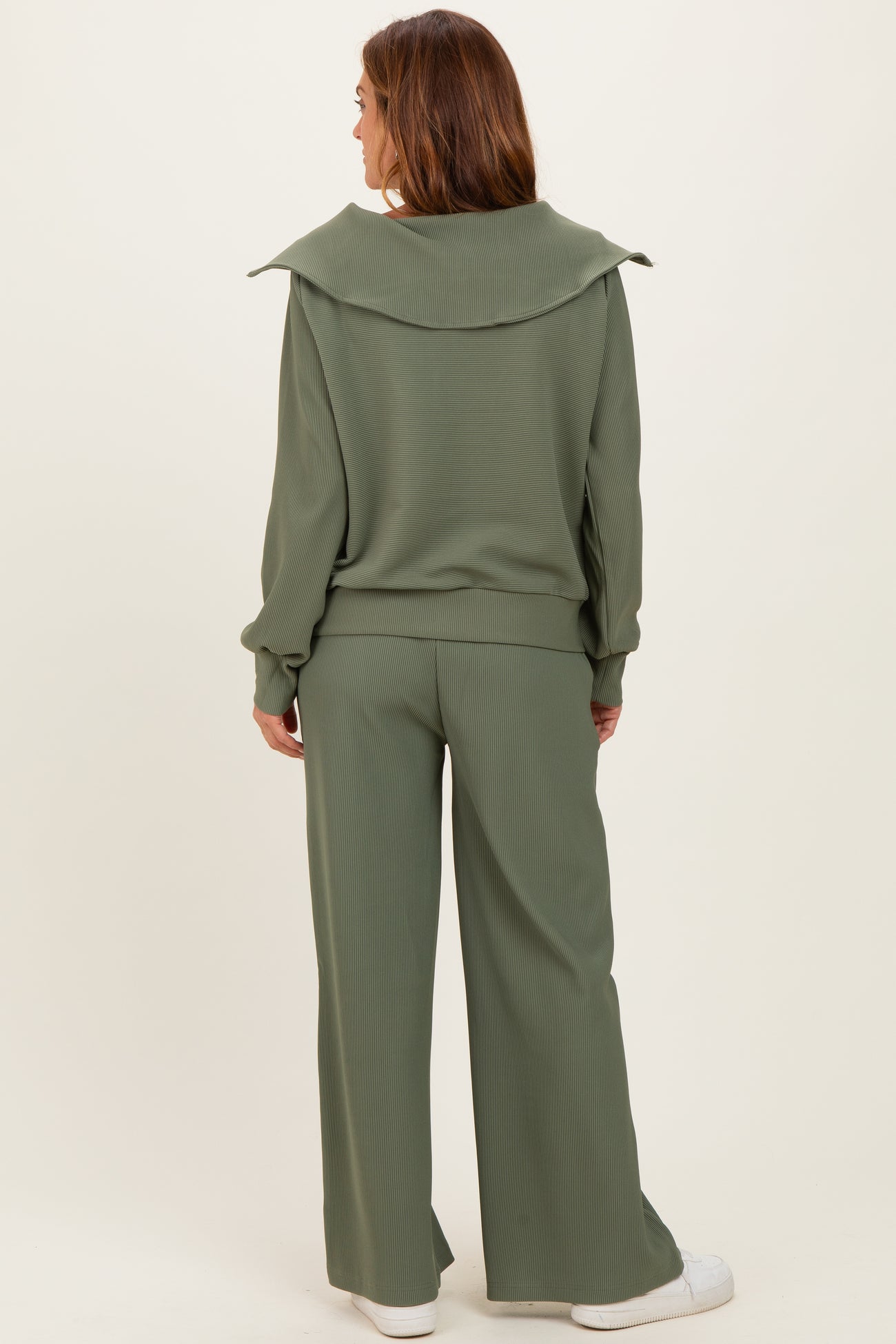 woman wearing an olive green ribbed lounge set featuring a relaxed top with a wide collar and matching wide-leg pants