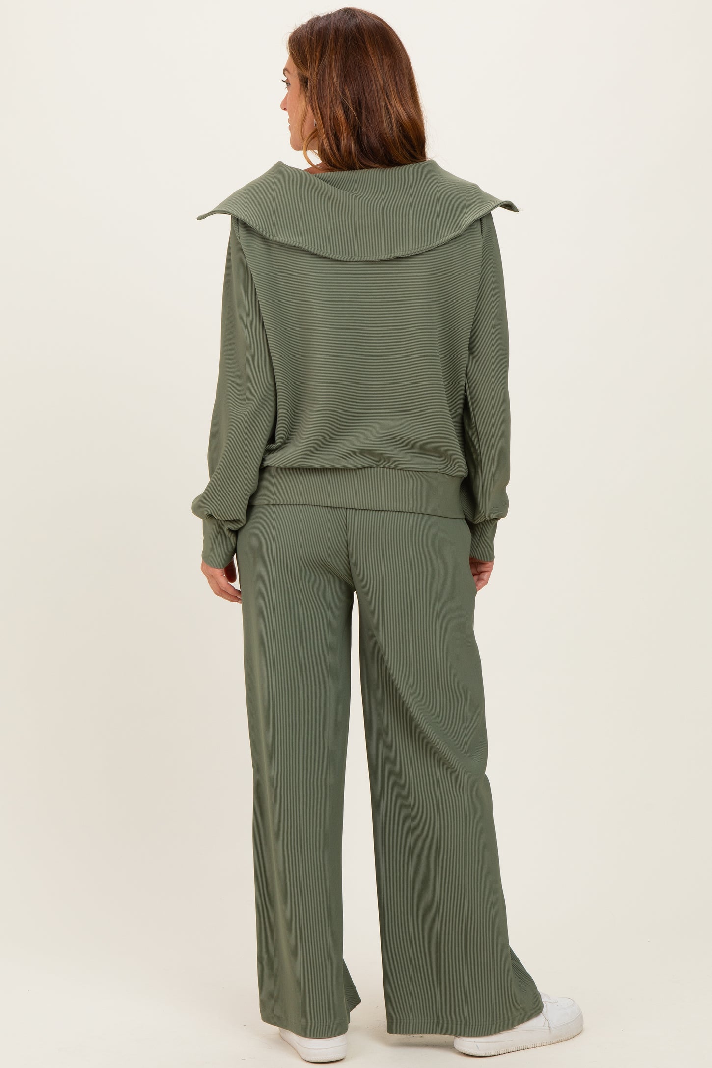 woman wearing an olive green ribbed lounge set featuring a relaxed top with a wide collar and matching wide-leg pants