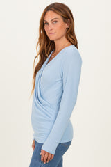 woman wearing a light blue long sleeve top with a draped front and slim fit, styled with jeans