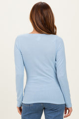 woman wearing a light blue long sleeve top, viewed from the back, with a fitted style and soft fabric