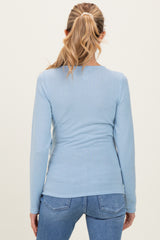 woman wearing a light blue long sleeve maternity top, viewed from the back with a fitted silhouette