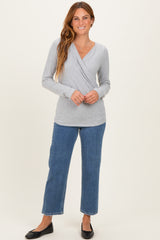 woman wearing a gray wrap long sleeve top paired with blue wide-leg jeans and black flats