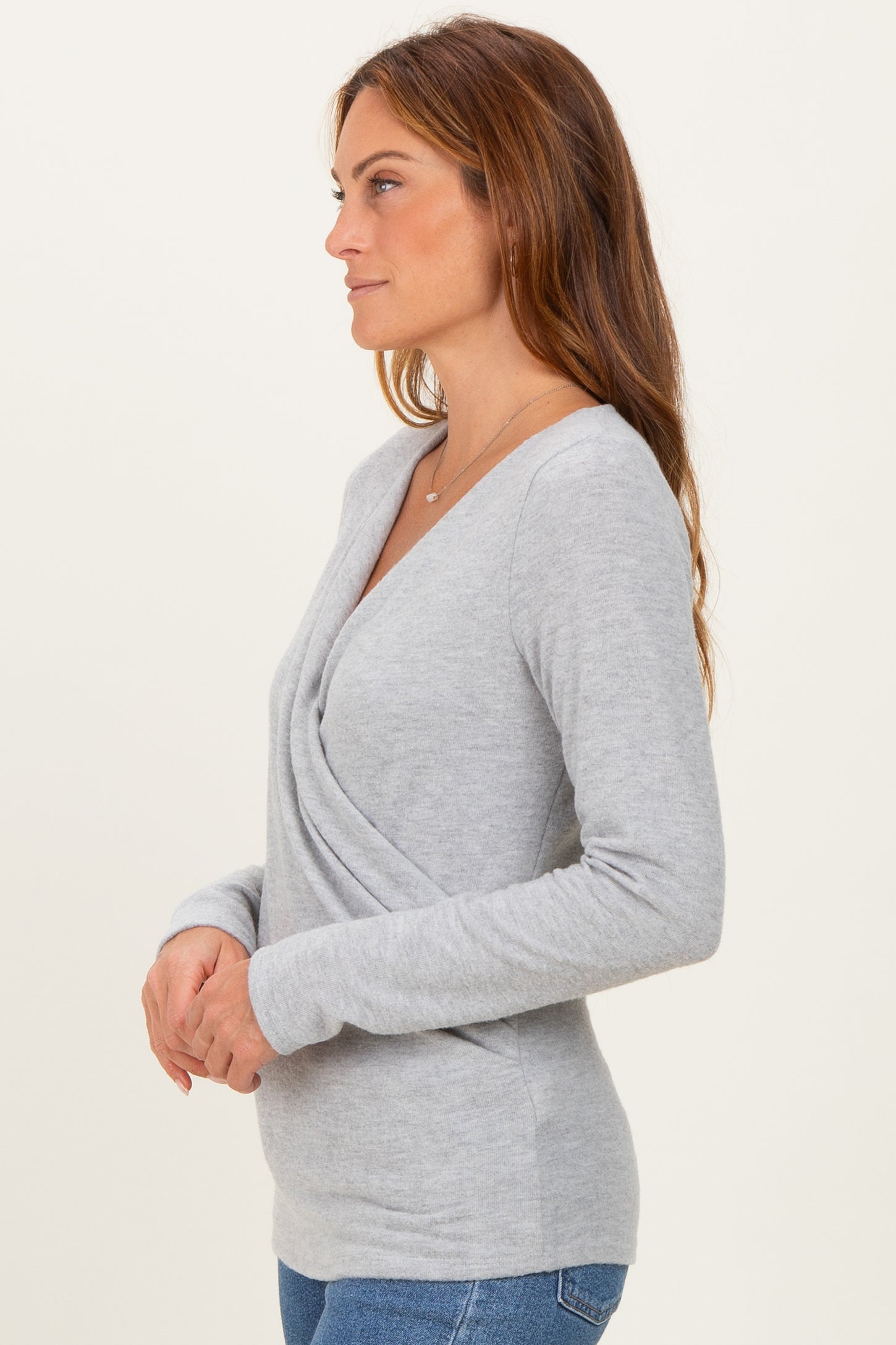 woman wearing a light gray long sleeve wrap top with a V-neckline and a fitted style