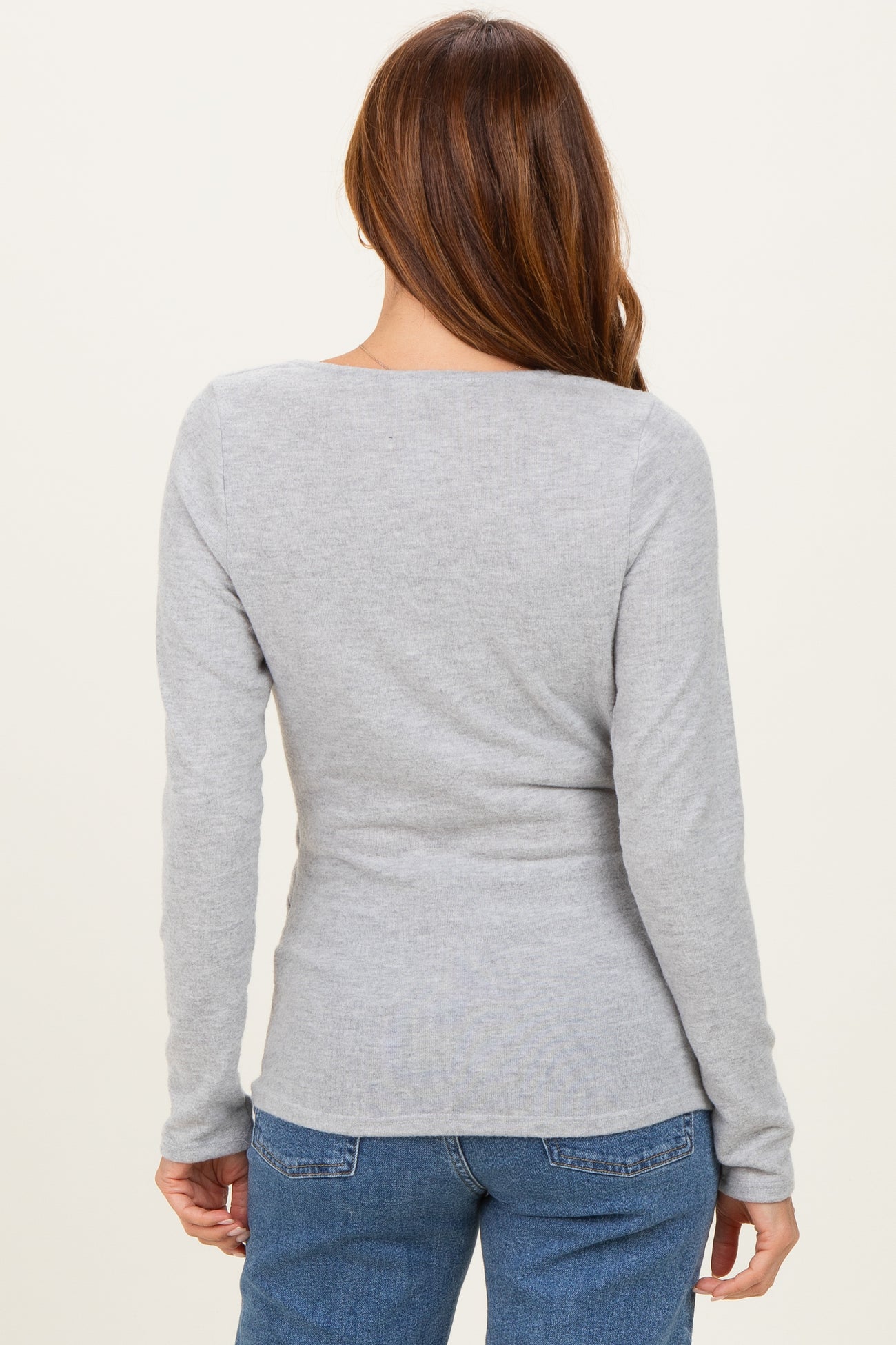 woman wearing a fitted grey long sleeve top, showing the back view with a scoop neckline and soft fabric