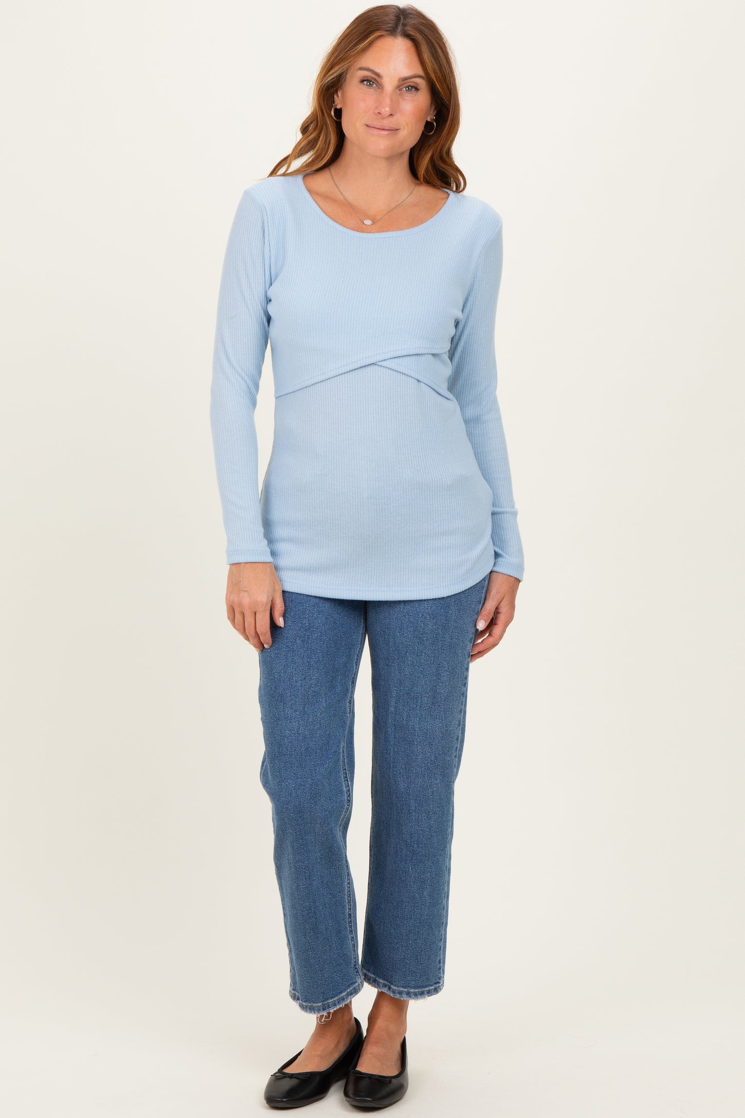woman wearing a light blue long sleeve ribbed top with a scoop neckline and paired with high-waisted jeans