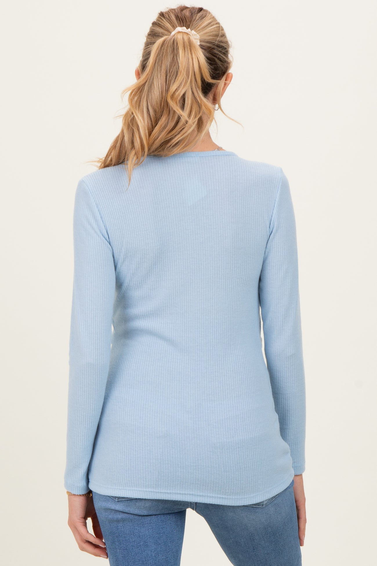 woman wearing a light blue long sleeve maternity top, viewed from the back