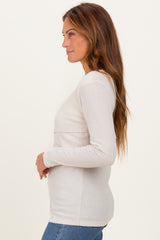 woman wearing a light beige ribbed long sleeve top with a fitted style and round neckline
