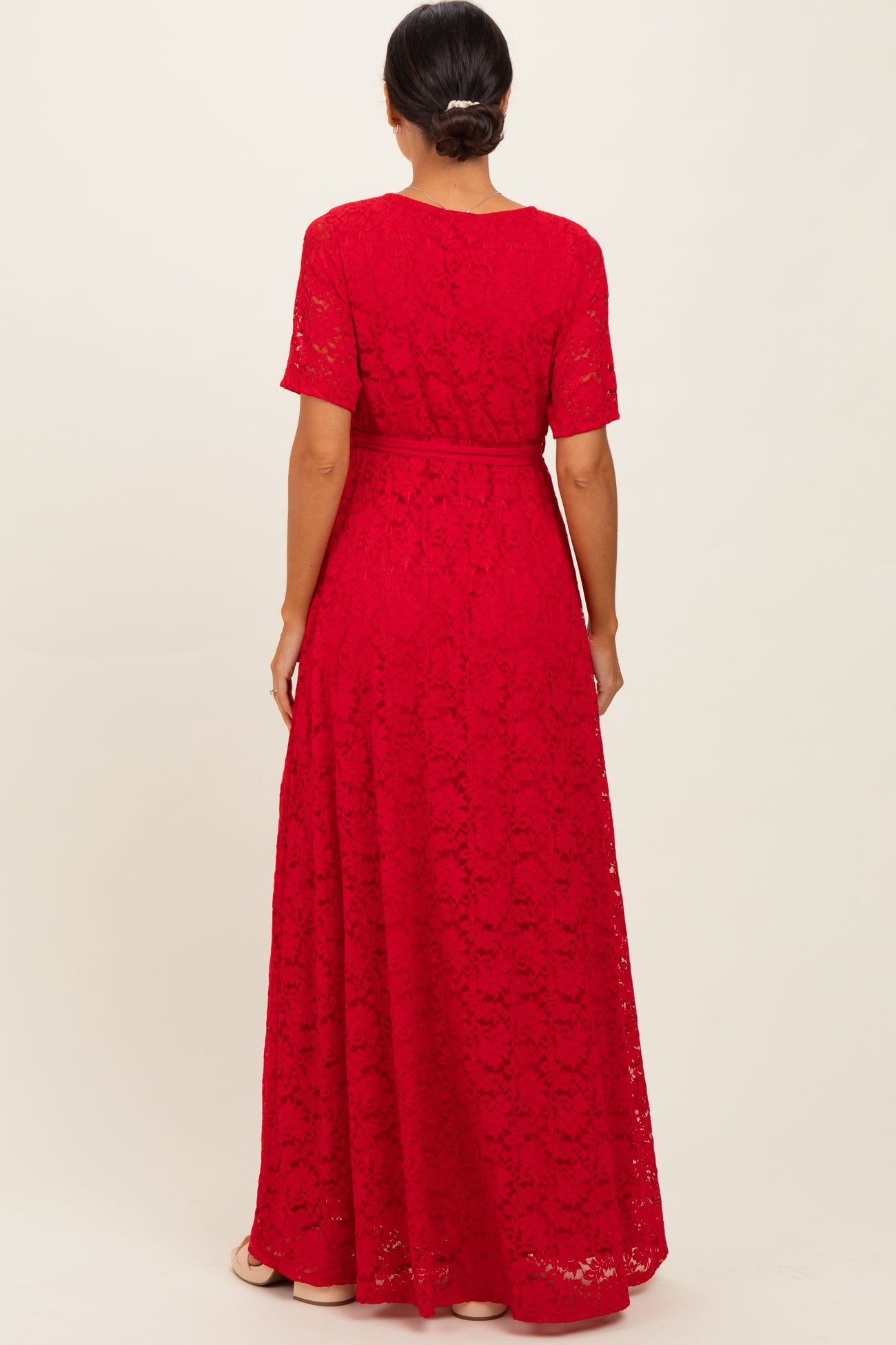 woman wearing a red lace maxi dress with short sleeves and a tie waist, viewed from the back