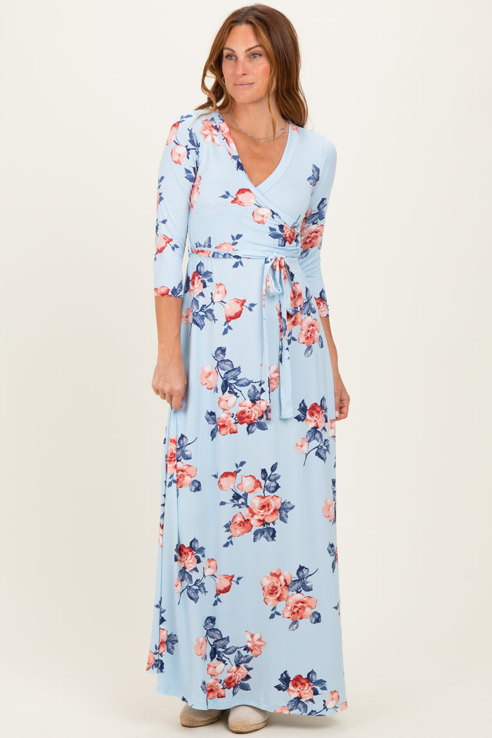 woman wearing a light blue floral wrap maxi dress with three-quarter sleeves and a tie waist