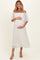 woman wearing a white off-the-shoulder maternity dress, gently holding her baby bump with pleated detail