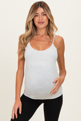 woman wearing a light gray maternity tank top and gently holding her baby bump