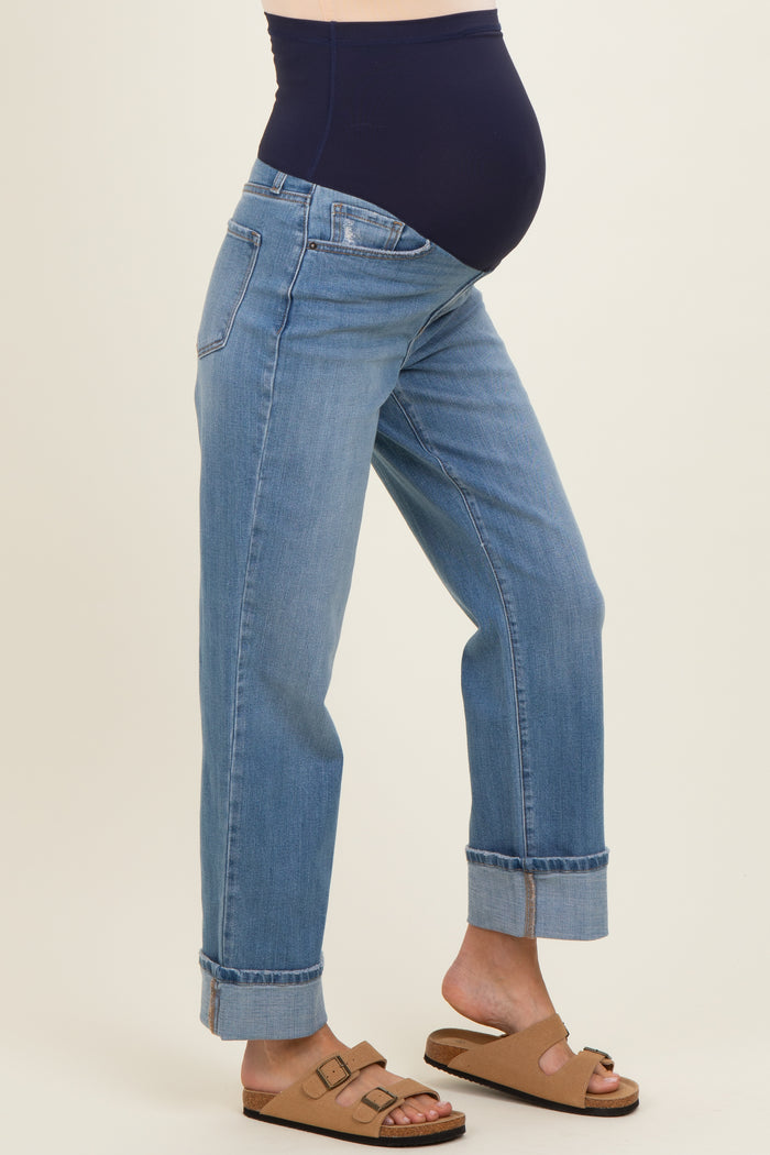 woman wearing a pair of light blue maternity jeans with a navy over-the-bump waistband and rolled cuffs, showing a baby bump