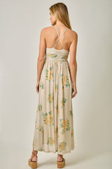 woman wearing a floral maxi dress with a low back and crisscross straps, showing a relaxed fit and flowy fabric