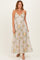 woman wearing a light beige floral maxi dress with a v-neckline and spaghetti straps