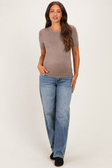 woman wearing a light brown short sleeve maternity top and blue jeans, showing a baby bump