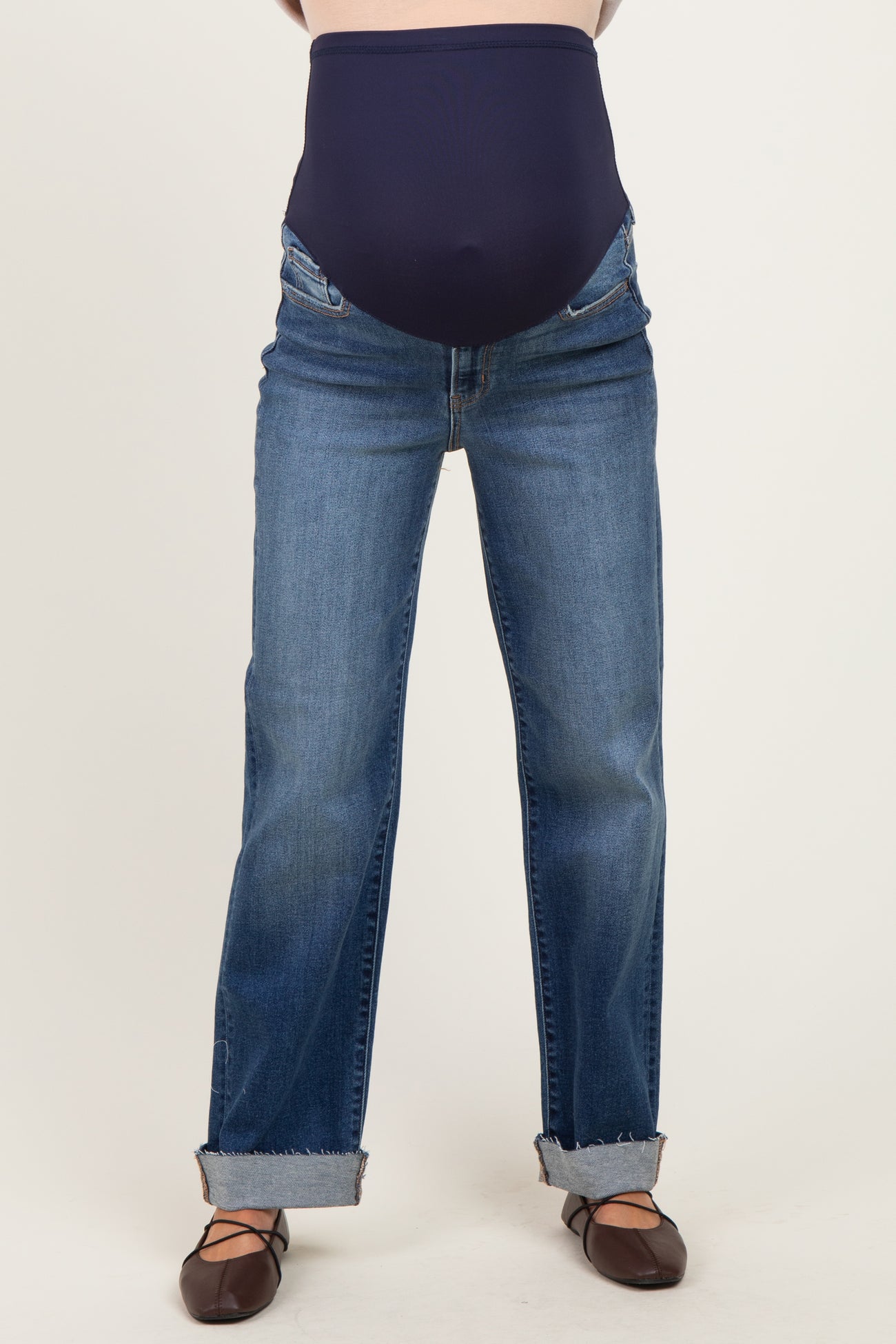 woman wearing a pair of maternity jeans with a dark blue over-the-bump panel and cuffed hem