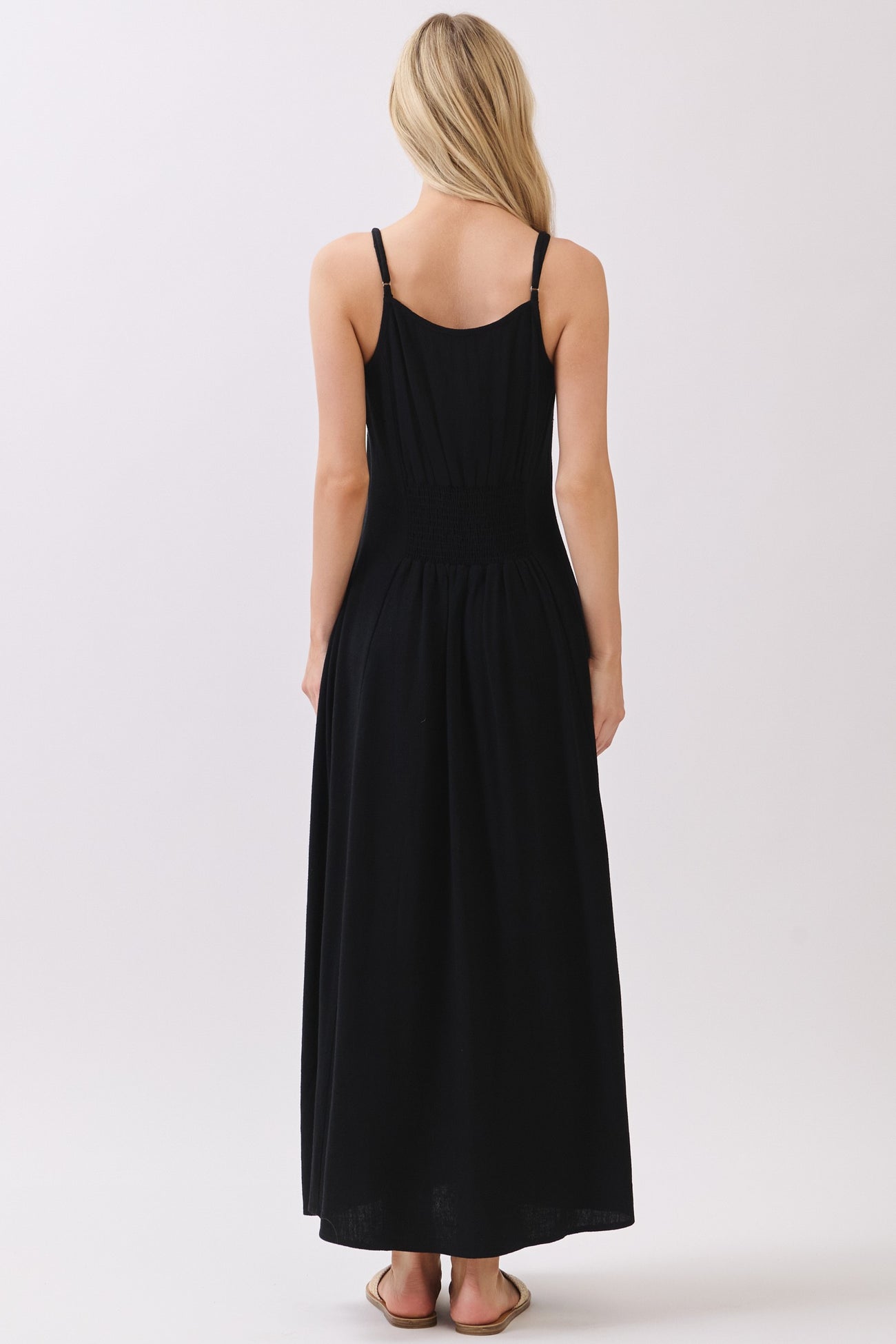 woman wearing a black sleeveless maxi dress with a smocked back and a flowy skirt