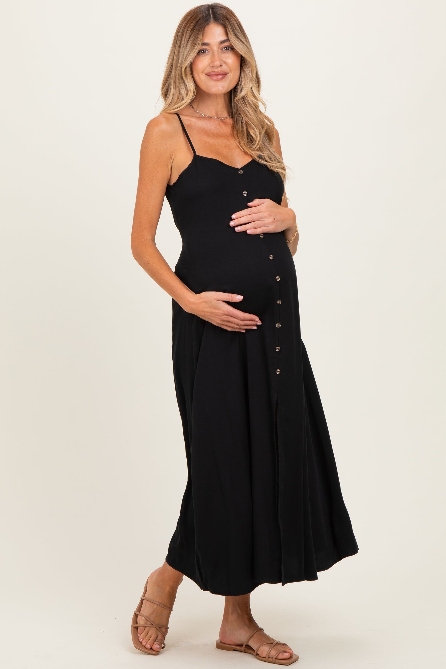 woman wearing a black maternity maxi dress with button details and holding her baby bump