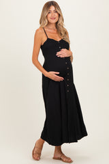 woman wearing a black maternity maxi dress with button details and holding her baby bump