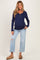 woman wearing a navy blue long sleeve henley maternity top and light wash distressed jeans with a visible baby bump