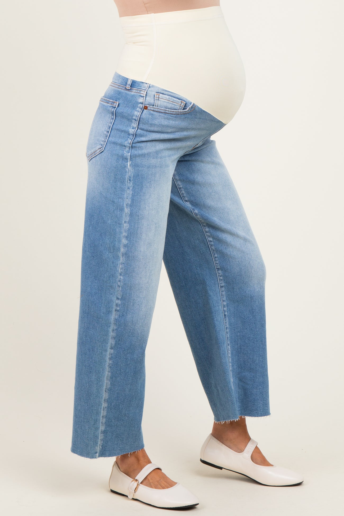 woman wearing light blue wide-leg maternity jeans with a stretchy belly panel, showing a baby bump
