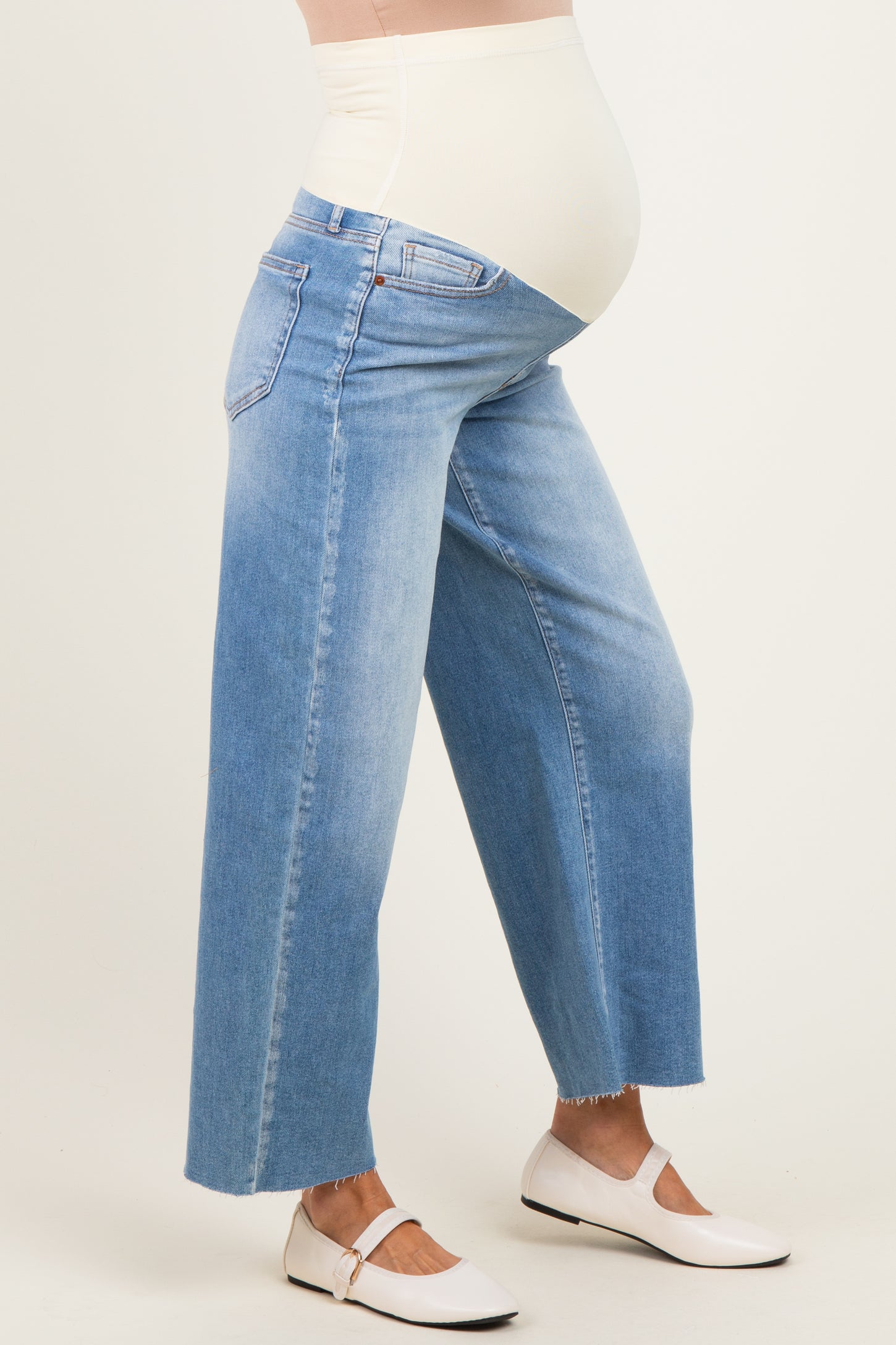 woman wearing light blue wide-leg maternity jeans with a stretchy belly panel, showing a baby bump