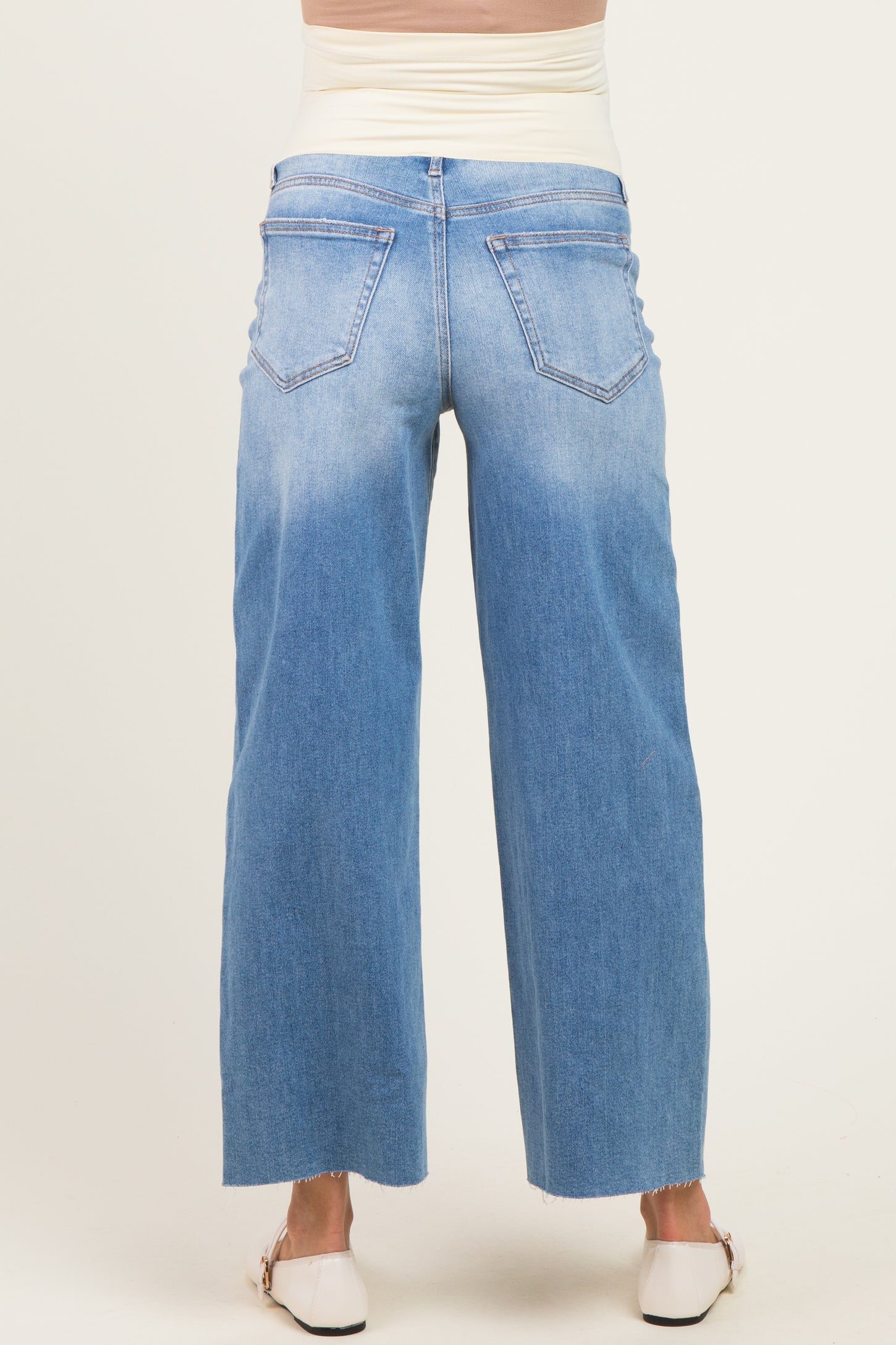 woman wearing light blue maternity wide-leg jeans with a raw hem and a stretchy waistband, showing a baby bump