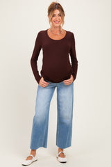 woman wearing a brown long sleeve maternity top and light blue wide-leg jeans with a visible baby bump
