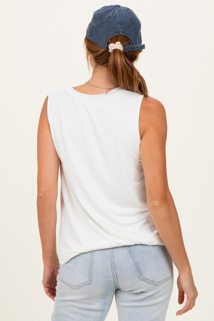 woman wearing a white sleeveless top with a relaxed fit and blue cap, showing the back view
