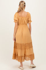 woman wearing a mustard yellow maternity dress with short sleeves and lace detailing on the hem