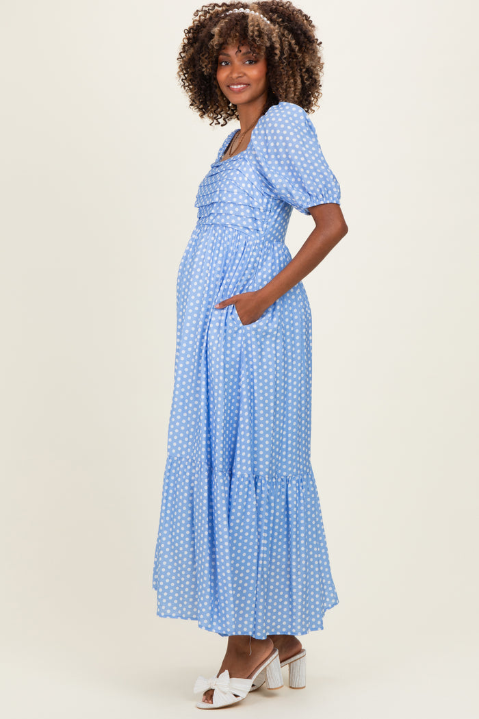 woman wearing a light blue polka dot maternity maxi dress with puff sleeves and pockets, showing her baby bump