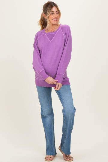 woman wearing a purple maternity sweater with a relaxed fit and paired with light blue flared jeans