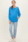 woman wearing a vibrant blue maternity sweatshirt with a relaxed fit and front pocket, paired with light wash jeans and white sneakers