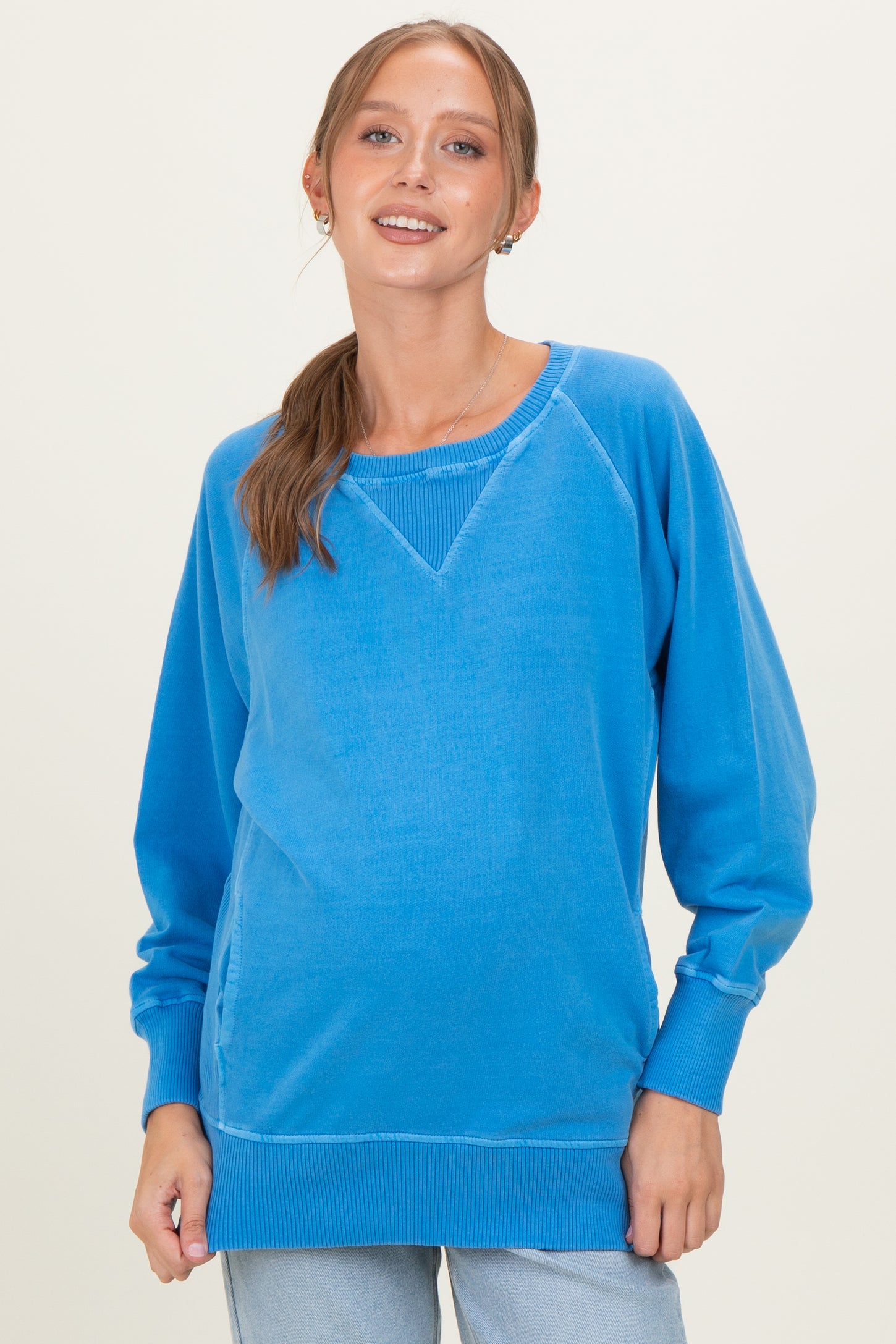 woman wearing a blue long sleeve maternity sweatshirt with a relaxed fit and a baby bump visible
