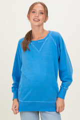 woman wearing a blue long sleeve maternity sweatshirt with a relaxed fit and a baby bump visible
