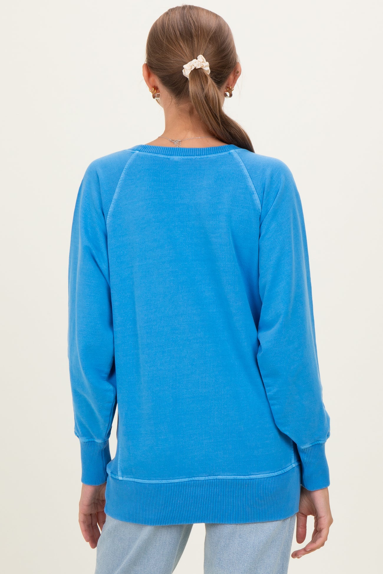 woman wearing a bright blue maternity sweatshirt with a relaxed fit, showing the back view