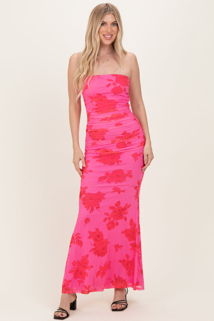 woman wearing a pink strapless maxi dress with red floral print and ruching detail
