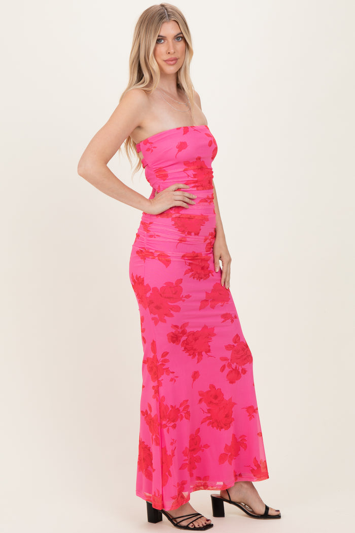 woman wearing a strapless hot pink maxi dress with red floral print and ruched detailing